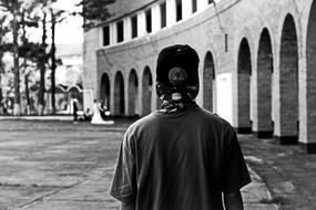 Black and white photo, of a guy with the cap, near the architecture