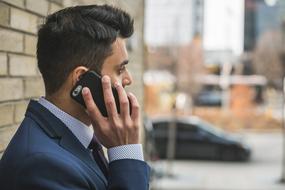 businessman talking on the phone near the wall