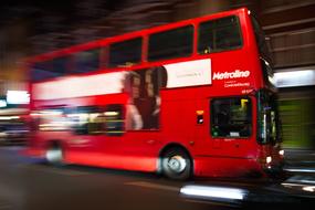 red bus on the streets of london in blurred background