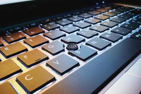 black laptop keyboard under lamp light, close-up