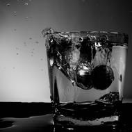 monochrome photo of euro coins in a glass of whiskey