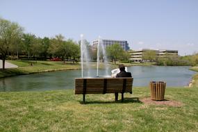 Businessman, with the newspaper, sitting on the bench in the business park, near the fountain