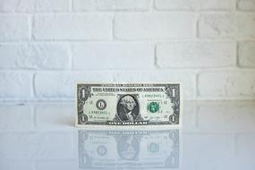 one dollar bill on white brick wall background