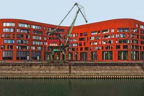 Red building and red and green crane, at blue sky on background