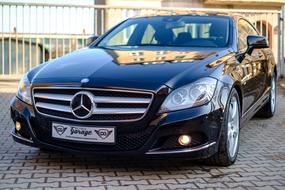 Beautiful, shiny, black Mercedes Cls car, on the pavement, near the fence, in light