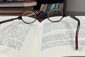 Glasses on the pages of the open book, among other colorful books