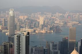 Cityscape of Hong Kong, with the shore with mountains, in smoke