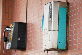 two old payphones on the wall of the house