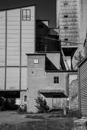 Black and white photo of the empty factory, among the other buildings, on the landscape