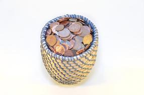 Close-up of the colorful and shiny coins in the beautiful basket, on the white surface