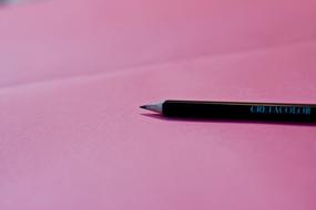 Close-up of the black pencil, on the pink surface