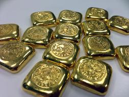 Close-up of the shiny gold bars with patterns, on the white surface