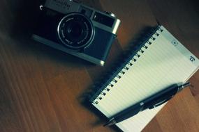 Camera Notepad Pen on a wooden table