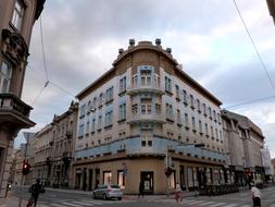 Landscape of the city with cars and people, among the colorful buildings, under the clouds