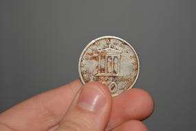 old greek coin in hand close up on gray background