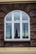 Close-up of the window of the building, with reflections of the buildings