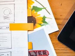 Colorful pictures and drawing near the tablet, on the wooden table