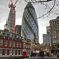 Beautiful Gherkin, among the other beautiful and colorful buildings in London, England, under the clouds