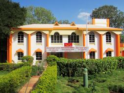Colorful Postmaster General's Office, among the beautiful, green plants in Dharwad, India