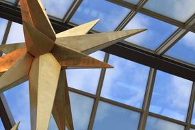 Figure of the shiny star in the building with windows, with view of the blue sky with clouds