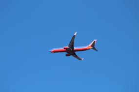 red passenger plane high in the sky