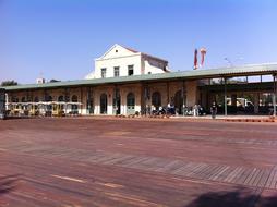 Landscape of the railway station building with people, in sunlight, under the blue sky