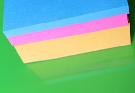 Close-up of the stack of the colorful sticky notes with the reflection in green surface