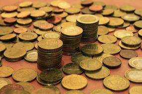Stacks of the shiny, metal coins among the piles, on the orange surface