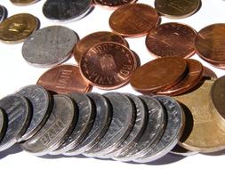 Pile of the colorful, shiny, metal coins, on the white surface, in light