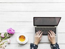 hands writing E-Mail on a laptop and Tea flower