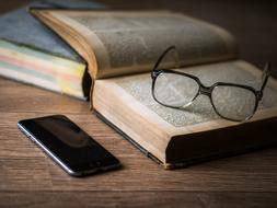 glasses on an old book and a smartphone on the table