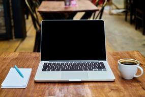 notebook for notes, a laptop and a cup of coffee on a table in a cafe