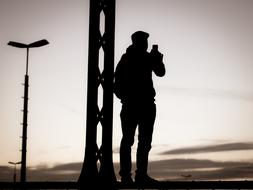 evening photo of a man standing by a lamppost