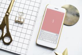 Aerial view of the shiny tools, notebook and smartphone with smile, on the white surface