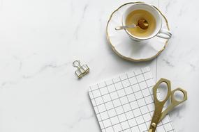 tea and scissors with notebook on a desk