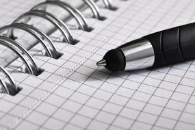 closeup picture of the black pen lies on a notebook