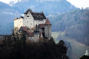 panoramic photo of a medieval castle on a background of a mountain forest