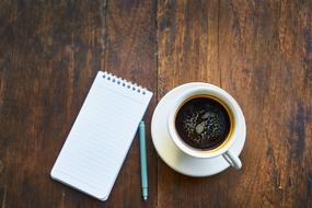 small notebook, pen and cup of coffee on the table