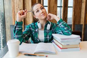 Beautiful young girl student, sitting at the table with the books and notebooks