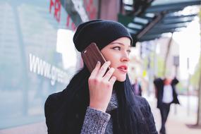 woman in black hat talking by the phone