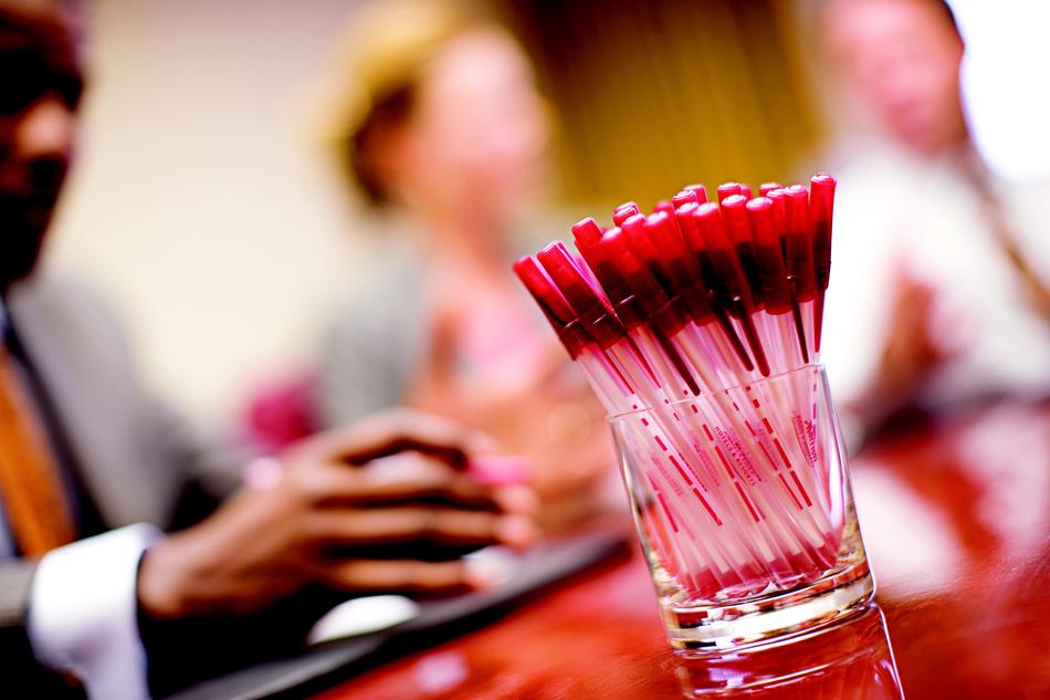 Colorful pens, in the glass, on the table on the meeting, among the people