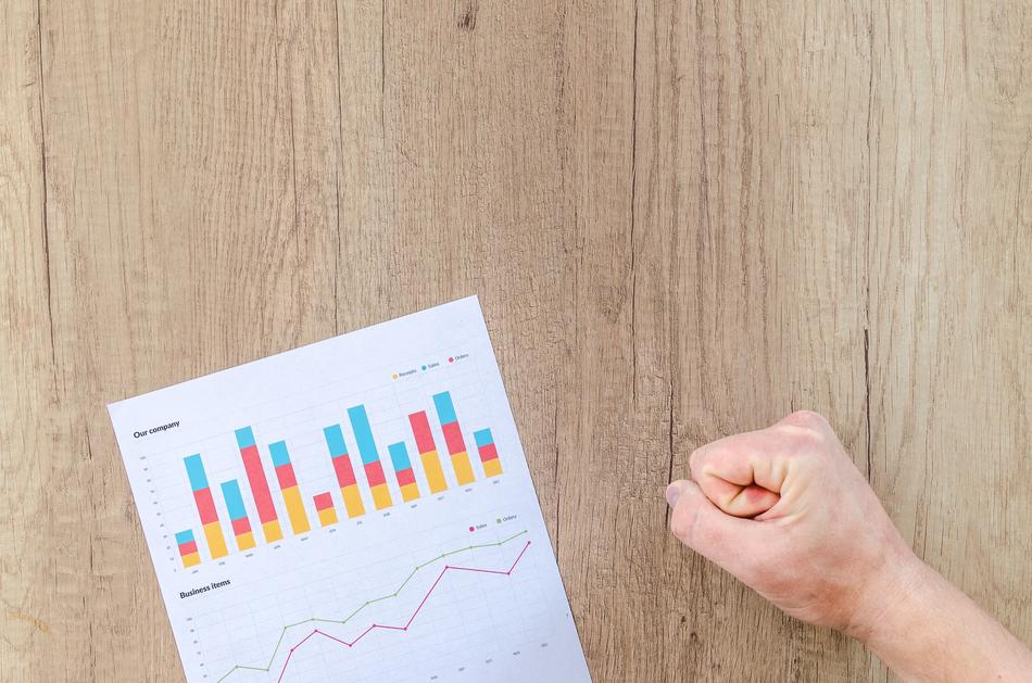 finance chart on paper and human fist on the wooden surface