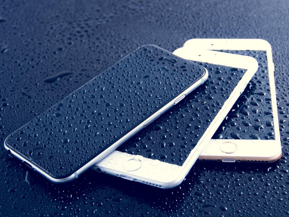 stack of three Iphones at dark wet surface