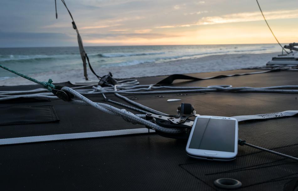 White phone on a wire near the water at colorful sky background