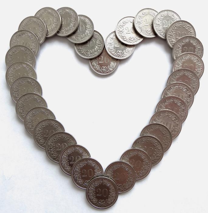 Heart, made of the glossy, metal coins, on the white surface