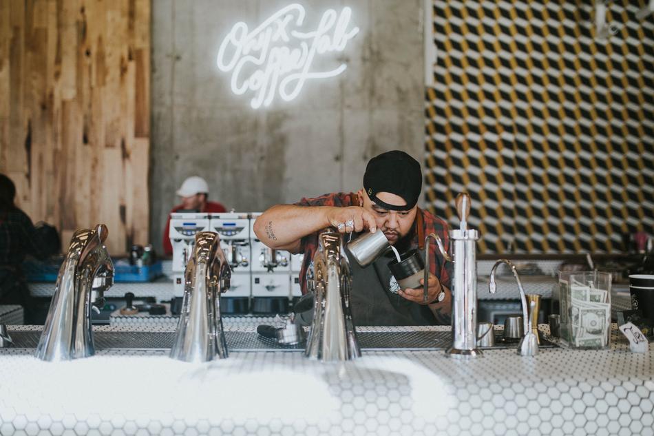 Bartender man in black cap, making a coffee behind the bar counter