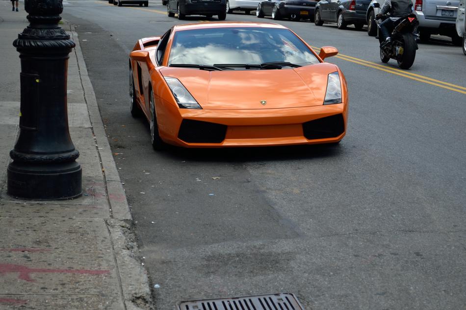 Beautiful, orange, glossy Lamborghini car on the road, near the other vehicles