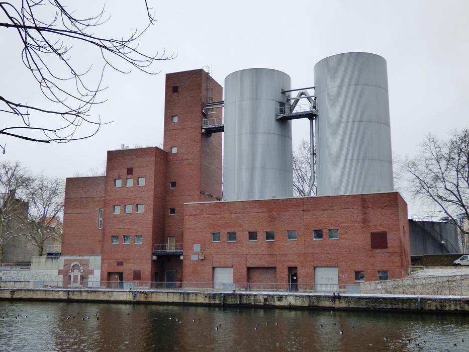 Brick factory building with the silos, on the shore, among the trees