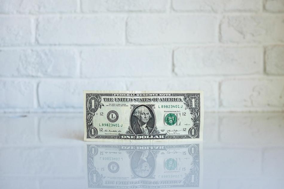 one dollar bill on white brick wall background