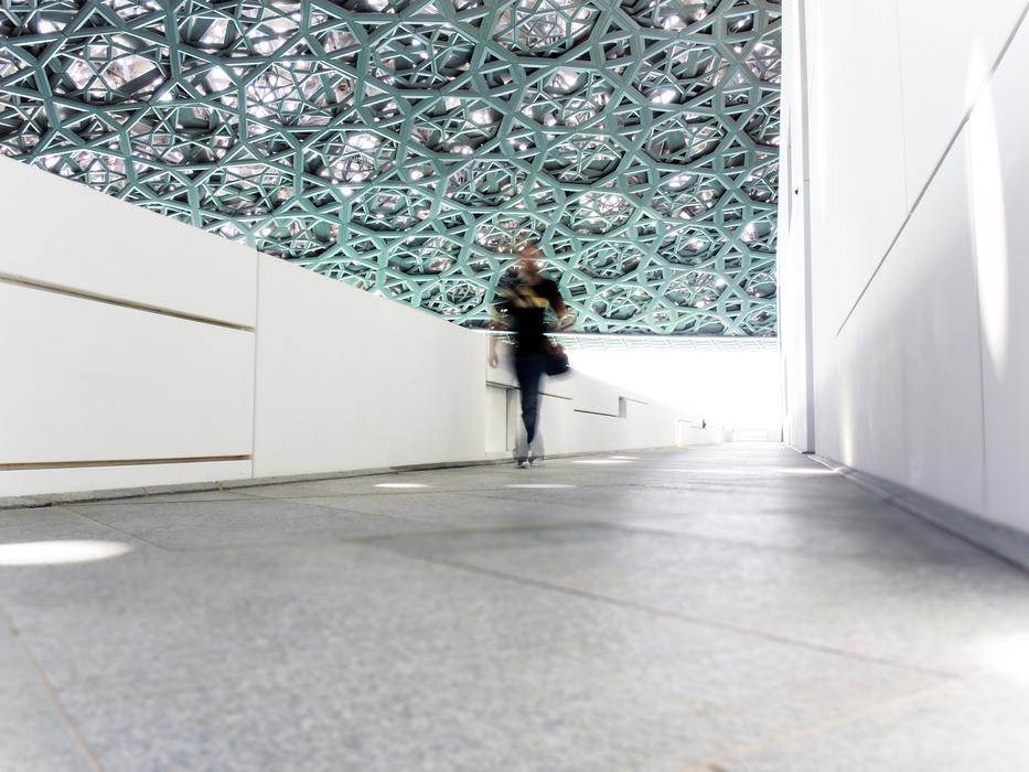 Person, walking in the Louvre building, in Abu Dhabi, UAE, with the lights